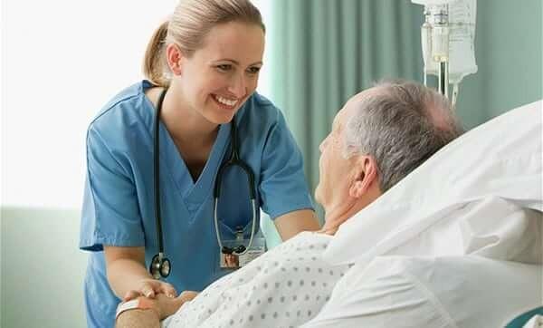 A nurse smiling at an elderly patient in a hospital bed