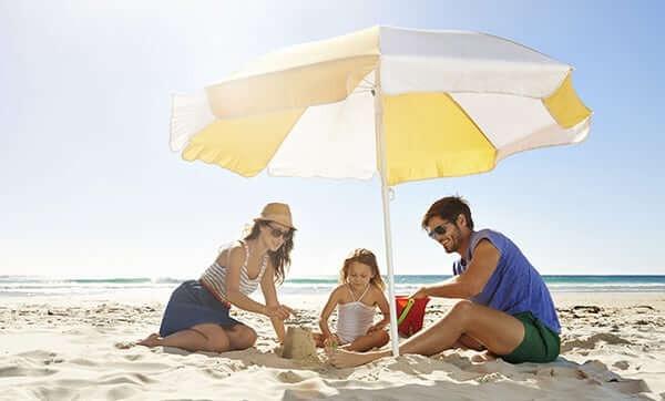 a family of three under an umbrella building sandcastles in Myrtle Beach